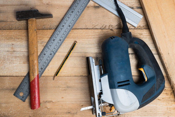 A top view of a setsquare, a hammer and  other repairing equipments on a wooden surface
